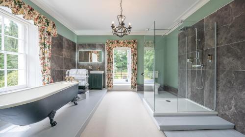 baño con bañera y ducha y lámpara de araña. en Pantybeiliau House Bed & Breakfast en Gilwern