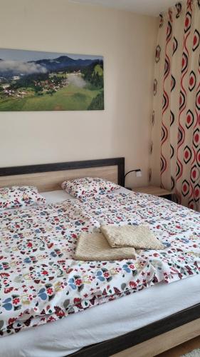 a bed with a flowered blanket with two pillows on it at Apartment PineWood *** in Vyšné Ružbachy