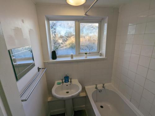 a bathroom with a sink and a bath tub and a window at LTK Basildon in Nevendon