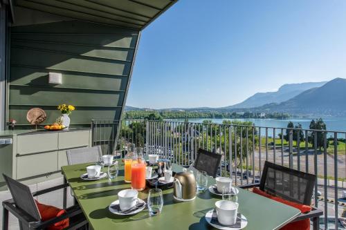 una mesa y sillas en un balcón con vistas al agua en Le Tresorium, en Annecy