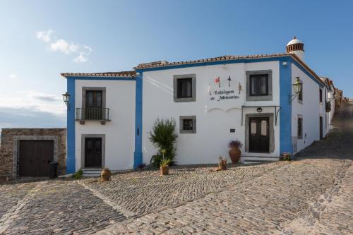 un edificio blanco y azul en una calle adoquinada en Estalagem de Monsaraz, en Monsaraz