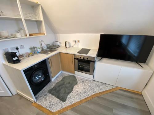 een kleine keuken met een wastafel en een wasmachine bij Cosy flat in London in Londen