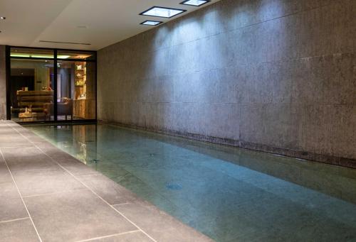a swimming pool in a building with a concrete wall at M de Megève in Megève