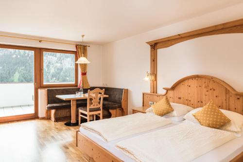 um quarto com 2 camas, uma secretária e uma mesa em Residence Rumanon em Ortisei