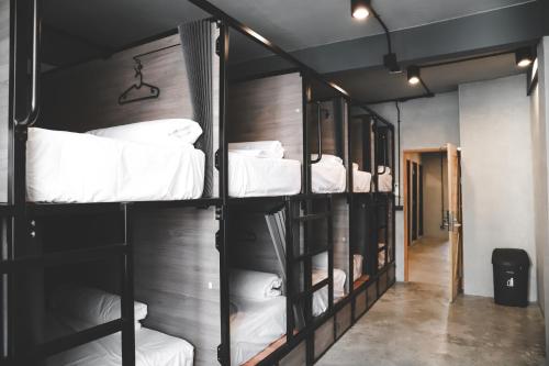 a room with three bunk beds with white sheets at The Cube Hostel Khaosan in Bangkok