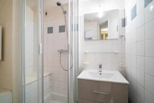 uma casa de banho branca com um lavatório e um chuveiro em LAtiPic em Barèges