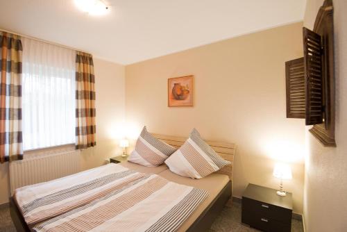 ein Schlafzimmer mit einem Bett mit zwei Kissen und einem Fenster in der Unterkunft Ferienwohnung Jacobs EG in Norddeich