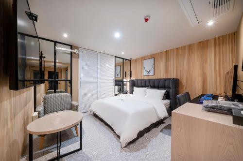 a bedroom with a white bed and a desk and chair at Gorilla Hotel in Wonju