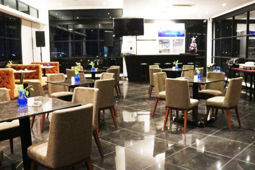 a restaurant with tables and chairs and a television at Surabaya River View Hotel in Surabaya