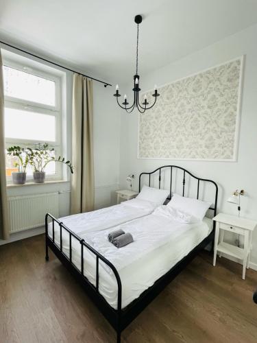 Un dormitorio con una cama con sábanas blancas y una lámpara de araña. en Pistacjowy - Apartamenty Smart Projekt, en Tarnów