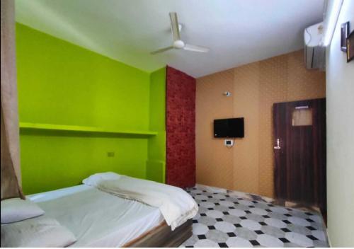 a green room with a bed and a tv at Hotel TSR By WB Inn in Agra
