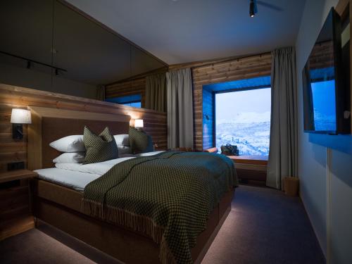 a bedroom with a bed and a large window at Skarsnuten Mountain Resort & SPA in Hemsedal