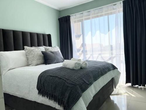 a bedroom with a bed with a large window at Cozy Self Catering Apartment with Golf Course Views, Jackal Creek Golf Estate in Roodepoort