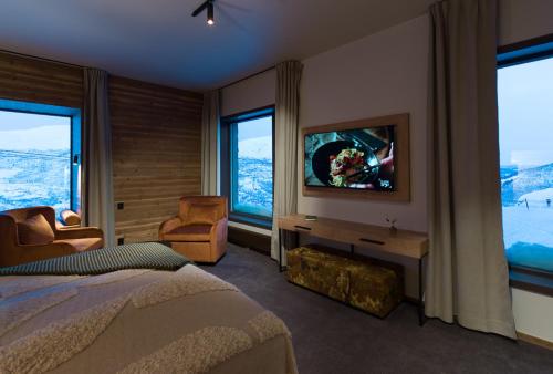 a bedroom with a bed and a tv and some windows at Skarsnuten Hotel and Spa by Classic Norway Hotels in Hemsedal