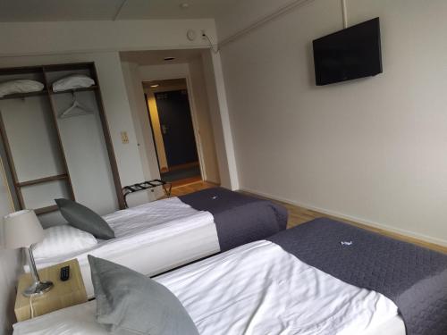 Habitación de hotel con 2 camas y TV de pantalla plana. en Hotel Kalkstrand, en Pargas
