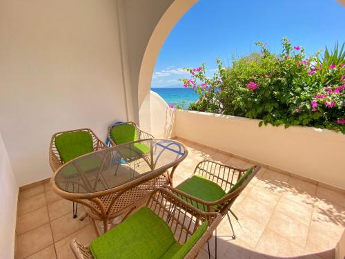 a balcony with a table and chairs and the ocean at The Beachhouse Apartments in Vaia
