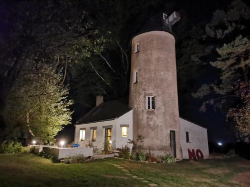 una casa bianca con una torre dell'orologio di notte di Le moulin de La Retardière a Orvault