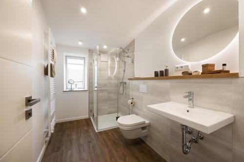 een badkamer met een wastafel, een toilet en een douche bij My Suite Leesch - Hotel & Restaurant nahe Büsum - Hunde herzlich willkommen in Reinsbüttel