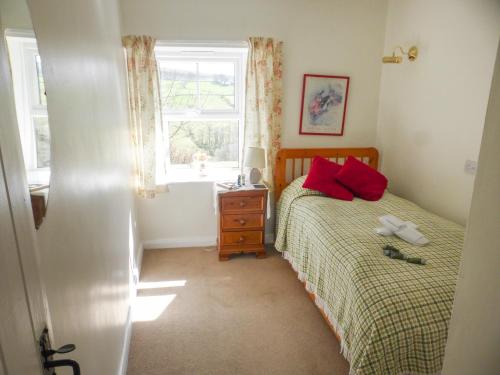 a bedroom with a bed with red pillows and a window at Sally End in Ravenstonedale
