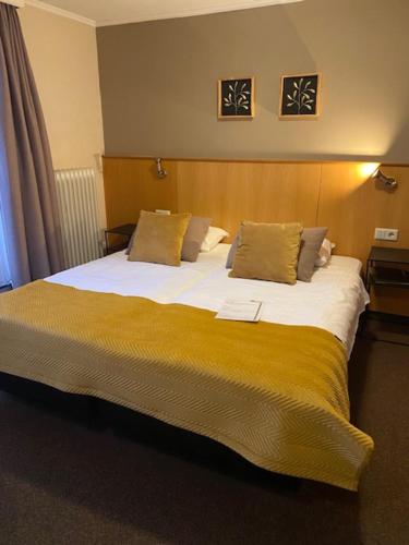 a bedroom with a large bed with a yellow blanket at Hotel Het Anker in Heythuysen