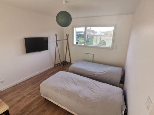 1 Schlafzimmer mit 2 Betten und einem Flachbild-TV in der Unterkunft Maison neuve au calme à 2 pas du Mans et des 24h. in Ruaudin