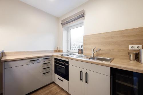 a kitchen with white cabinets and a sink and a window at My Suite Leesch - Hotel & Restaurant nahe Büsum - Hunde herzlich willkommen in Reinsbüttel