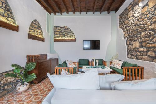a living room with white furniture and a stone wall at Philoxenia traditional house in Pastida