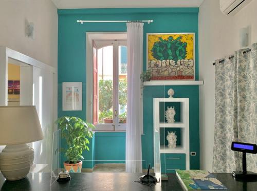 a living room with blue walls and a window at Hotel Posta in Siracusa