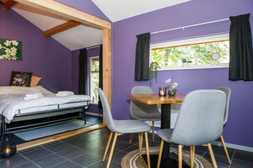 a bedroom with purple walls and a table and chairs at Het Wachterspunt / Herberg de Vrolijke Jager in Oirschot