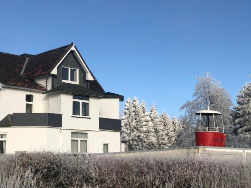 a white house with a red lighthouse in front of it at Berghotel HARZ in Hahnenklee-Bockswiese
