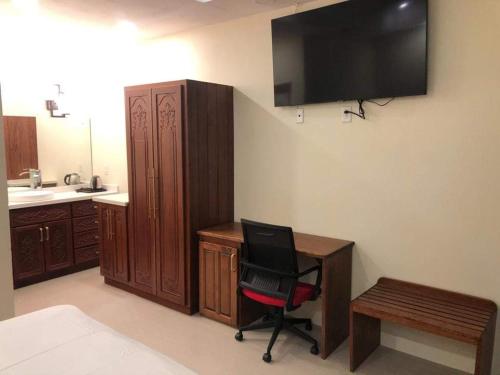 a room with a desk and a chair and a television at PESHERES INN & SPA in Bon Accord