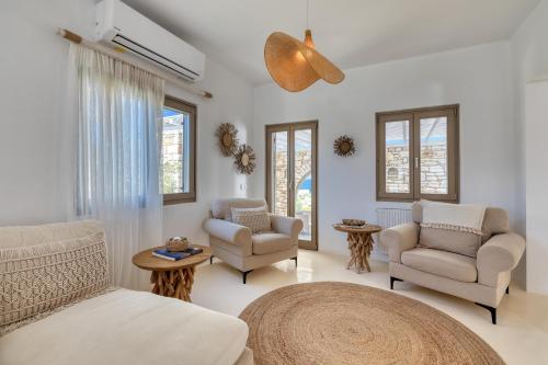 a living room with white furniture and windows at Amalgam Homes Paros in Ambelas