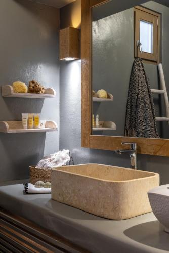 a bathroom with a stone sink and a mirror at Amalgam Homes Paros in Ambelas