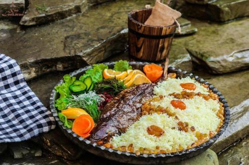 a plate of food with meat and vegetables on a table at Khan Lankaran Hotel in Lankaran