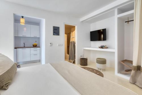 a white bedroom with a bed and a kitchen at Amalgam Homes Paros in Ambelas