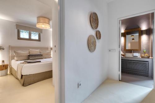 a white bedroom with a bed and a bathroom at Amalgam Homes Paros in Ambelas
