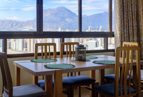 a dining room table with chairs and a view of the mountains at Sun&Beach View Apartments in Benidorm