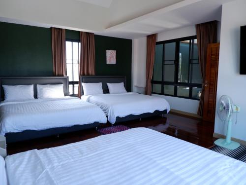 a bedroom with two beds and a green wall at Talaytime Pool Villa in Laem Sing