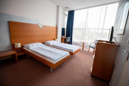 a hotel room with two beds and a tv at Hotel Sport in Karviná