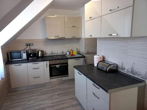 a kitchen with white cabinets and a black counter top at APARTMENT TONI / 2BEDROOMS in Varna City