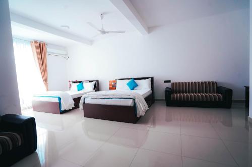 sypialnia z 2 łóżkami i kanapą w obiekcie Sun Ray Rest House w mieście Kalkudah