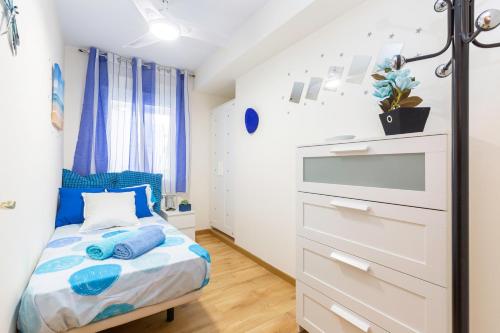 um pequeno quarto com uma cama com almofadas azuis em Apartamento Puente de Segovia em Madri