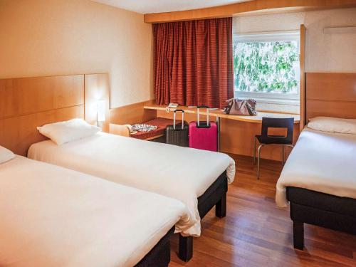 een hotelkamer met 2 bedden en een bureau bij ibis Belfort Danjoutin in Belfort