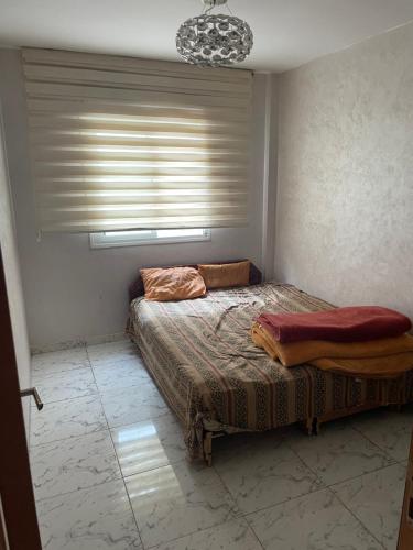 a bedroom with a bed and a window with blinds at Une bonne appartement in Casablanca