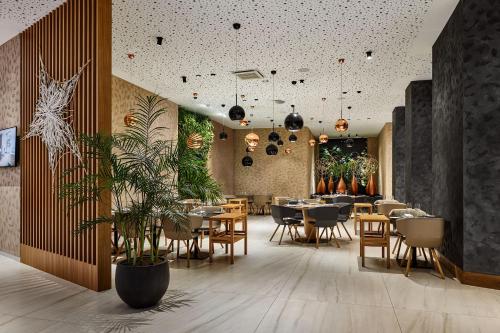 Hotel Passage في برنو: مطعم بالطاولات والكراسي والنباتات
