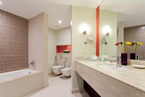 a bathroom with a tub and a sink and a toilet at Park Inn by Radisson Al Khobar in Al Khobar