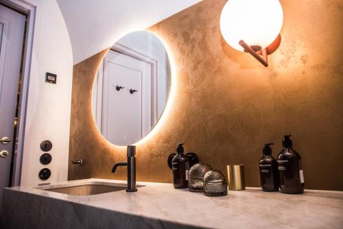 - un lavabo dans la salle de bains avec un miroir et des bouteilles sur un comptoir dans l'établissement Silma Retreat, à Haapsalu