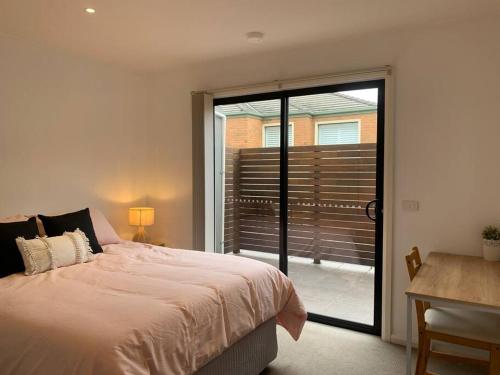 een slaapkamer met een bed en een glazen schuifdeur bij Affordable 2BR Apartment near Melbourne CBD in Maribyrnong