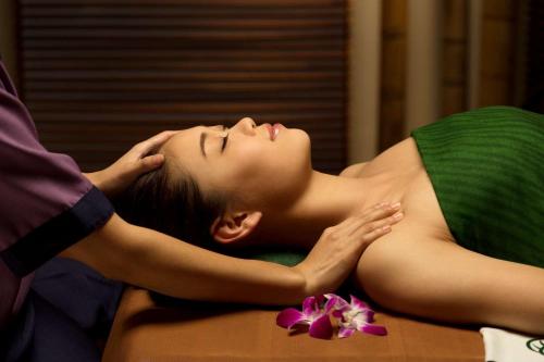 a woman laying on a bed with her head on a table at Banyan Tree Tamouda Bay in Fnidek