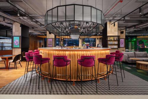 a bar with red chairs in a room at Hyatt Place Krakow in Kraków